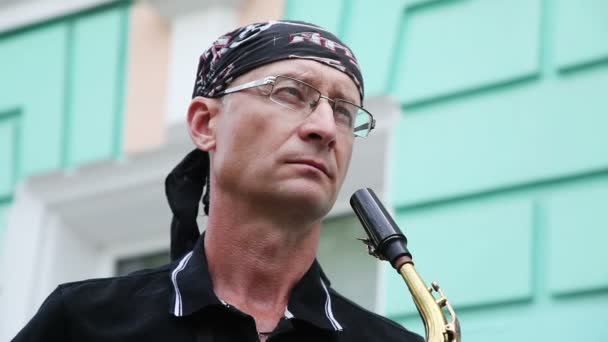 L'homme au bandana et au saxophone dans ses mains contre le mur . — Video