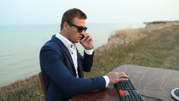 Zakenman controleren zijn dagboek tegen strand scène — Stockvideo