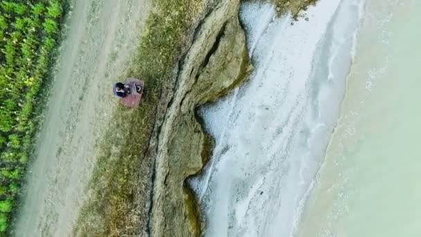 Um homem sentado numa secretária com um computador no penhasco junto ao mar. Subir drone . — Vídeo de Stock