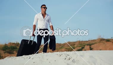 Çölde bir iş adamı. Genç bir adam bir takım elbise ve bir büyük Bagaj çanta çölde. İşadamı tatil için yolda. Beyaz kum. Bunaltıcı çöl.