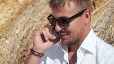 İş adamı ile bir dizüstü bilgisayar ve samanlıkta oturan telefonda konuşurken güzel eserlerinden benziyor. Yaz tatili şehir dışında. Her yerde çalışın. Serbest çalışma.