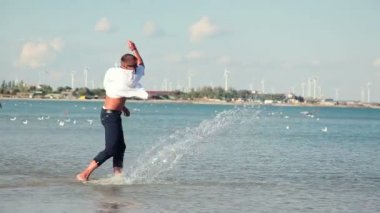 İş adamı iyi görünüyor beach diz yazarak iş elbiseli mutlu bir şekilde yürür, sıçramalarına yapma.