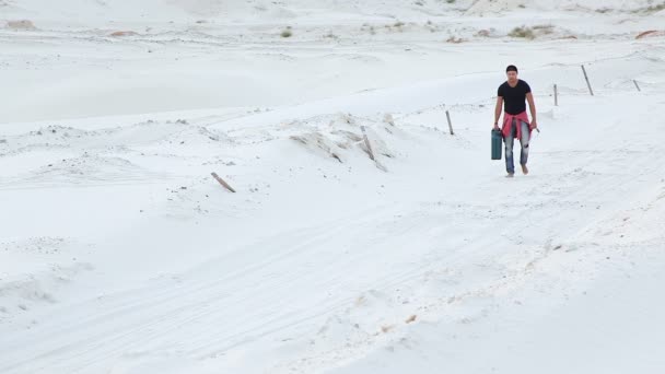 A young man goes through the desert with a canister of gasoline in search of fuel. — Stock Video