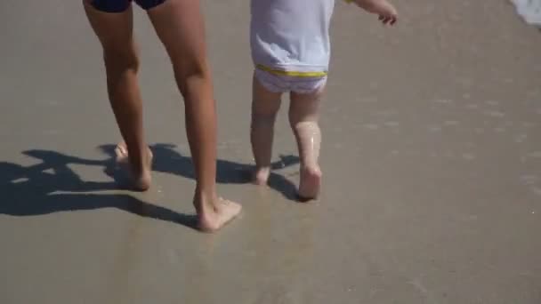 Dois irmãos caminham pela praia em um dia ensolarado . — Vídeo de Stock