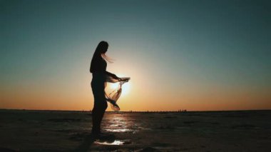 Gün batımı gökyüzünün arka planında siluet mutlu kadın.