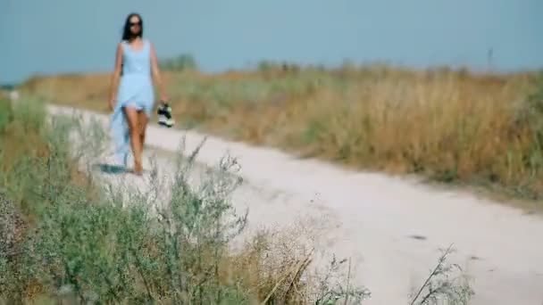 Slank meisje gaat door Sandy Road naar het strand — Stockvideo