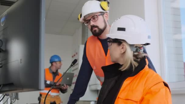 Frau arbeitet mit bärtigem Kollegen im Umspannwerk am Computer — Stockvideo