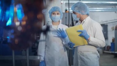 Üniformalı ve maskeli meslektaşlar otomatik taşıyıcıyı kontrol eder