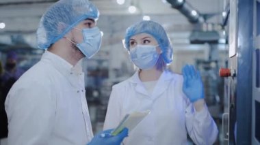 Paltolu ve maskeli müfettişler yeni ekipman yakınındaki verileri kontrol ediyor