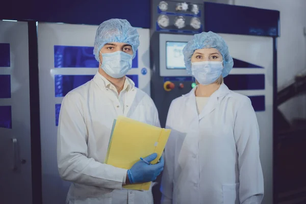 Üniformalı kadın ve erkek yeni ekipmanların yanında duruyor.