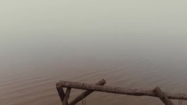 Boş ahşap salıncaklar durgun deniz suyunda duruyor.