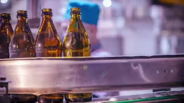 Конвейер перевозит стеклянные бутылки пива рядом с работниками магазина — стоковое видео