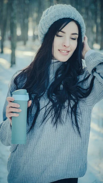 Elinde termosu olan genç bir kadının portresi.