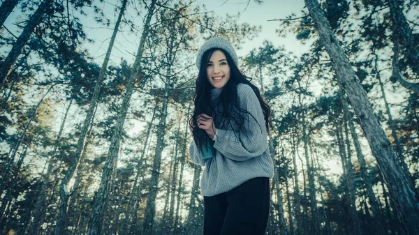 Kış ormanı ağaçlarının arka planındaki kadın.