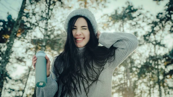 Genç esmer, kış ormanlarında kameraya surat yapar.