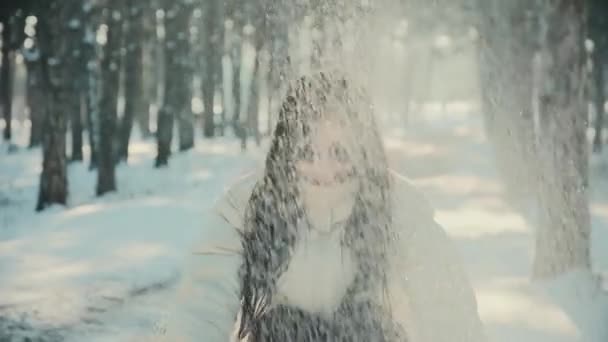 Ładna kobieta w okularach przeciwsłonecznych rzuca śnieg w zimowym lesie — Wideo stockowe