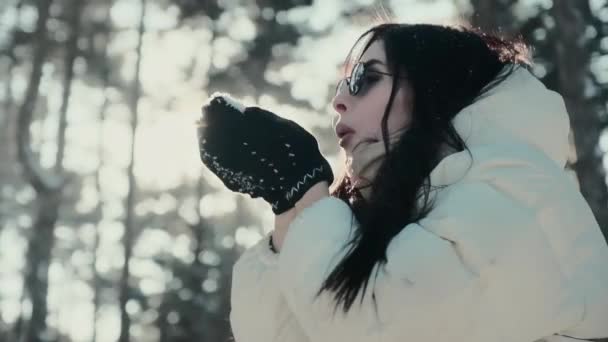 Frau mit Sonnenbrille pustet Schnee und amüsiert sich im Winterwald — Stockvideo