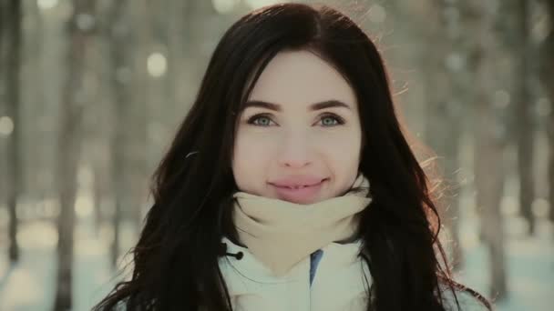 Aantrekkelijke vrouw in jas en sjaal glimlacht in de winter bos — Stockvideo