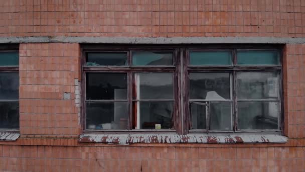 A fachada de uma casa velha com molduras de janela quebradas e vidro. — Vídeo de Stock