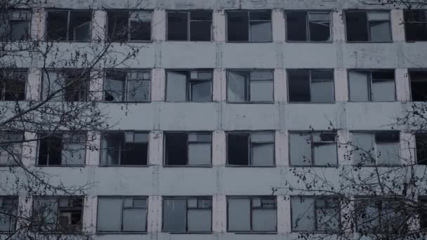 Exterior de um edifício vazio de vários andares. Molduras quebradas e vidros, desolação geral — Vídeo de Stock