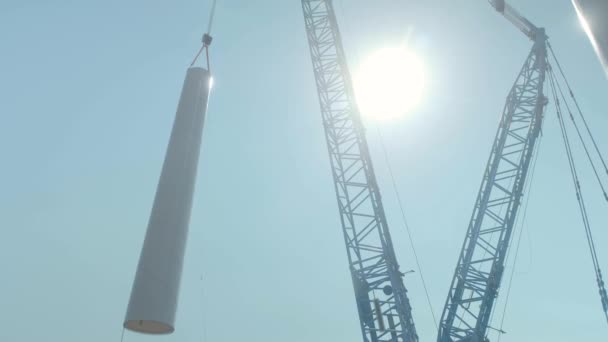 Żuraw samochodowy podnosi część składową turbiny wiatrowej na placu budowy — Wideo stockowe