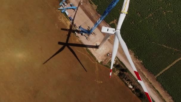 Guindaste de torre instala parte da lâmina da máquina de vento acima dos campos — Vídeo de Stock