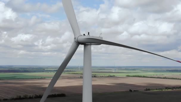 Los trabajadores caminan sobre el suelo del molino de viento contra el cielo nublado — Vídeos de Stock