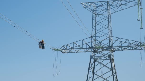 Medewerker repareert elektriciteitstransmissielijnen onder blauwe hemel — Stockvideo