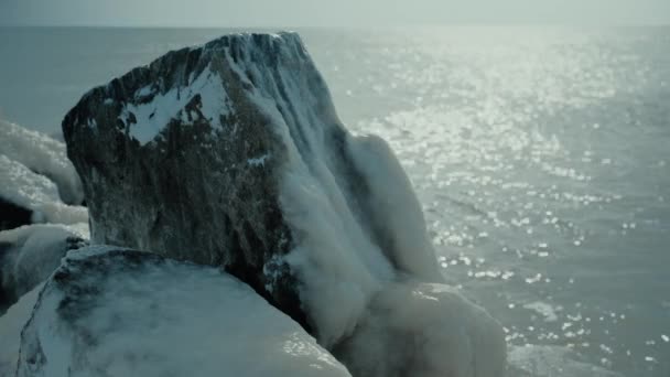 Ledový kámen pokrytý sněhem na pozadí moře — Stock video