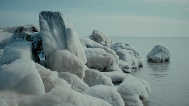 Obrovské kameny pokryté ledem na pláži klidného moře — Stock video