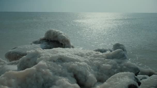 Jéggel borított sziklák a nyugodt, fényes óceán partján — Stock videók