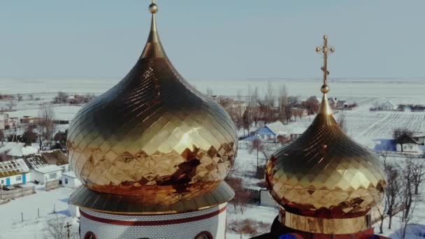 Золоті куполи православної церкви в селі в зимову снігову погоду.. — стокове відео
