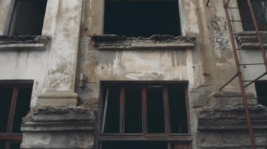 Paslı yangın merdivenleri olan terk edilmiş bina boyunca ilerleyin.