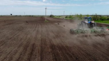 Kuşlar traktörün üzerinden uçar çiftçi tarlalarındaki toprağı yıkarlar.