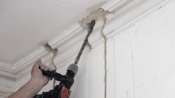 Workman fait un trou dans le plafond en travaillant avec une perceuse électrique — Video