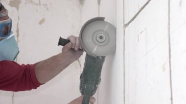 Handyman in respirator and goggles cuts wall with disc saw