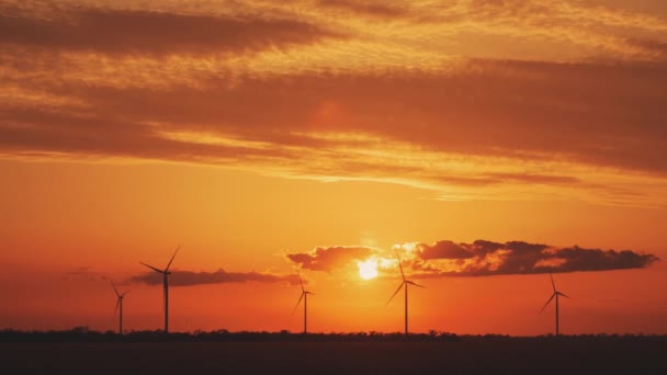 Silhouettes of windmills producing electricity at sunset — Stockvideo