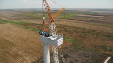 Yellow white crane installs rotor into generator container