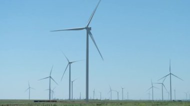 Powerful windmill farm generates electricity on green meadow
