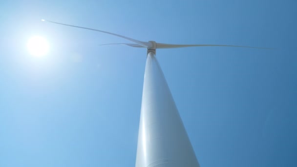 Windturbine wekt elektriciteit op tegen zonneschijf aan de hemel — Stockvideo