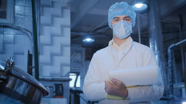 Un tecnólogo con máscara posa frente a la cámara en un taller de producción — Foto de Stock
