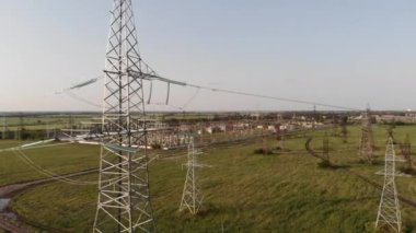 Yüksek voltajlı bir alt istasyonun arka planında yüksek voltajlı güç hattı var..