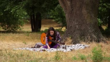 Kız bir gitar ile müzik besteler.