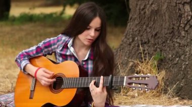 Kız bir gitar ile müzik besteler.