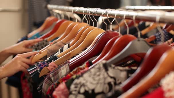 Happy girl choosing new garment in fashion store — Stock Video