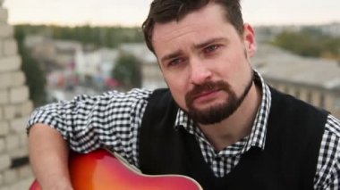 Adam çatıda bir gitar ile