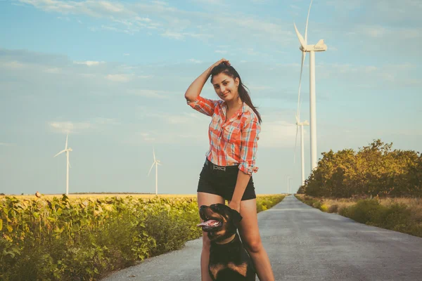 Girl with dog at sunset near the wind turbines.