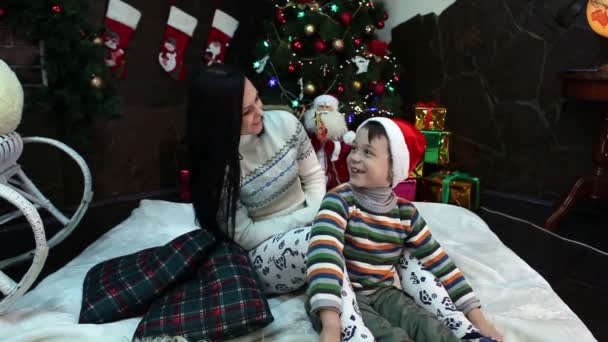 Año Nuevo. Navidad. Mamá e hijo cerca del árbol de Navidad y la chimenea. Acogedora casa, humor navideño . — Vídeo de stock