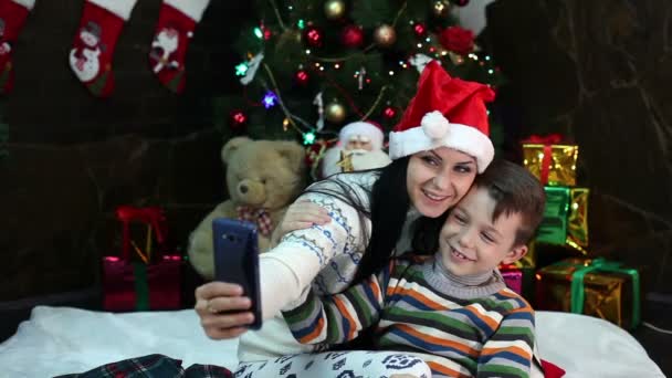 Año Nuevo. Navidad. Mamá e hijo cerca del árbol de Navidad y la chimenea. Acogedora casa, humor navideño . — Vídeo de stock