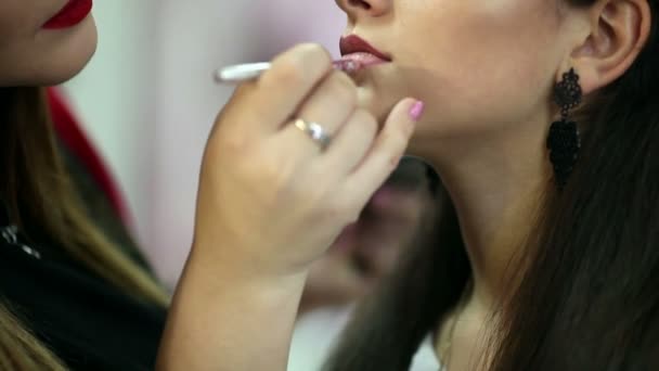 Una mujer guapa con maquillaje aplicado por un maquillador . — Vídeos de Stock